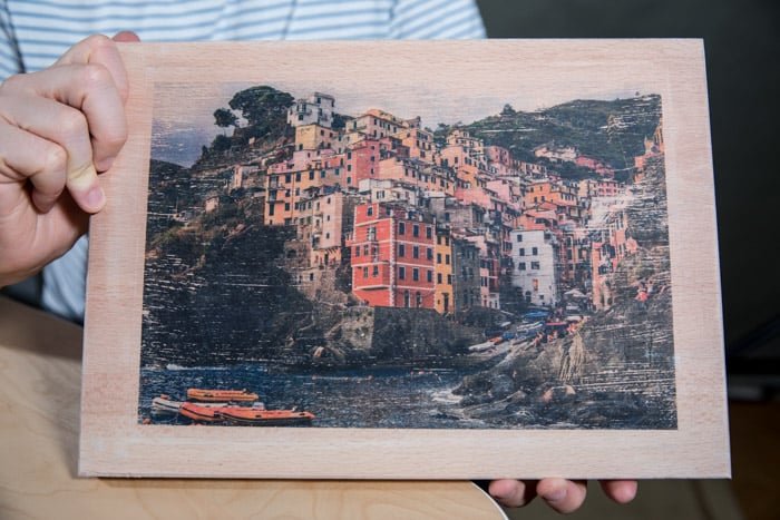 A man holding a photo printed on wood 