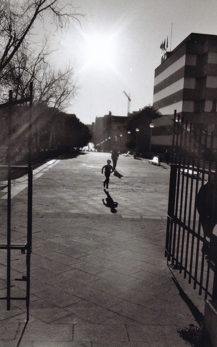 Black and white image of kid skipping down the street