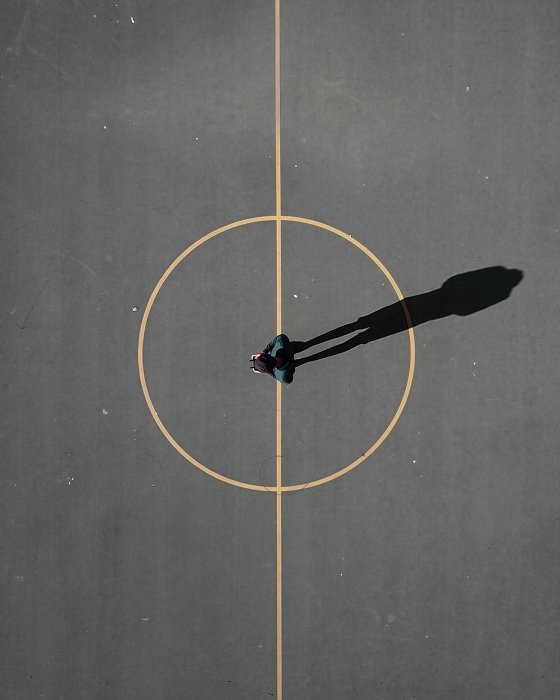 Arial shot of man standing in a center circle of a concrete pitch