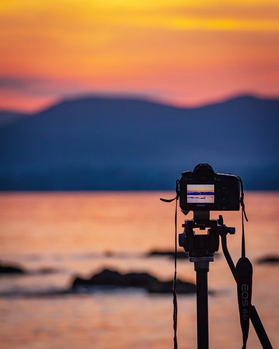 Camera on a tripod set to take a picture of a coastal sunset