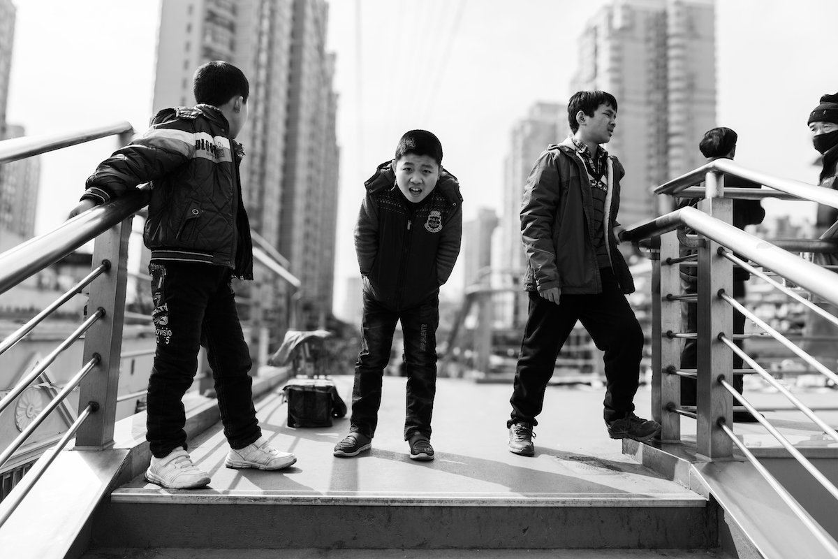 Black-and-white image of boys on a city platform with a circular bokeh lens blur in Adobe Lightroom