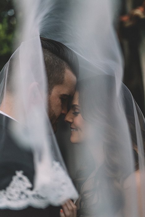A bride and groom behind a wedding veil 