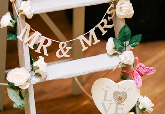 A white step ladder decorated with a Mr & Mrs sign for a wedding
