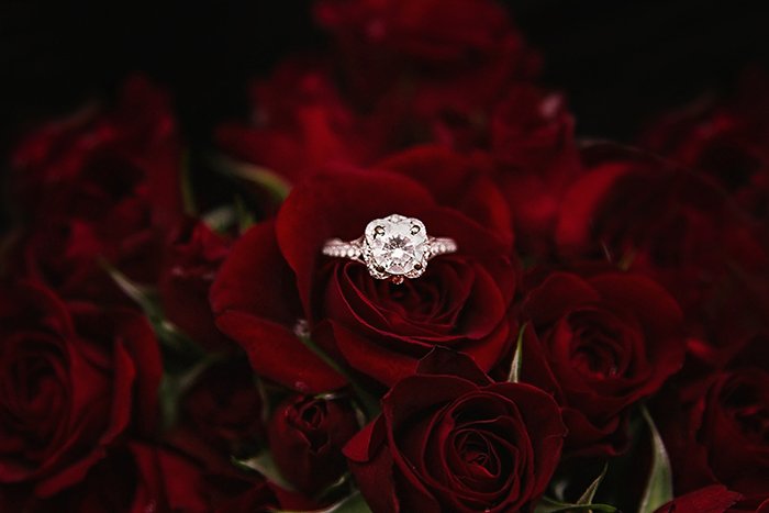 A wedding ring among dark red roses