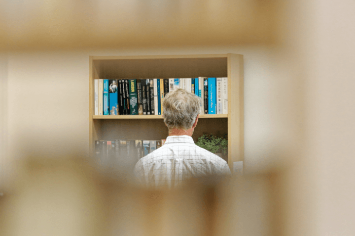 Picture of a man looking at books in a library 